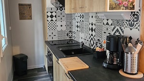A modern kitchen with a black countertop, wooden cabinets, and patterned backsplash.