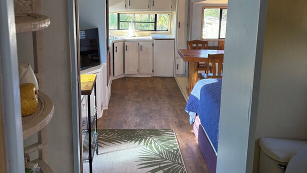 Interior d'una autocaravana compacta amb petita cuina, zona de menjador i espai per dormir.