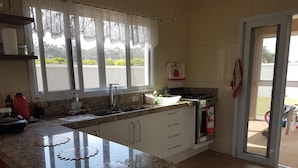 A kitchen with a granite countertop, white cabinets, a stainless steel sink, and a small oven. - House with heated pool. Santa Bárbara Resort Residence #casadecampo131 (Águas de Santa Bárbara)