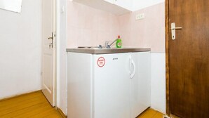 Een kleine keuken met een spoelbak, een fles afwasmiddel en een koelkast.