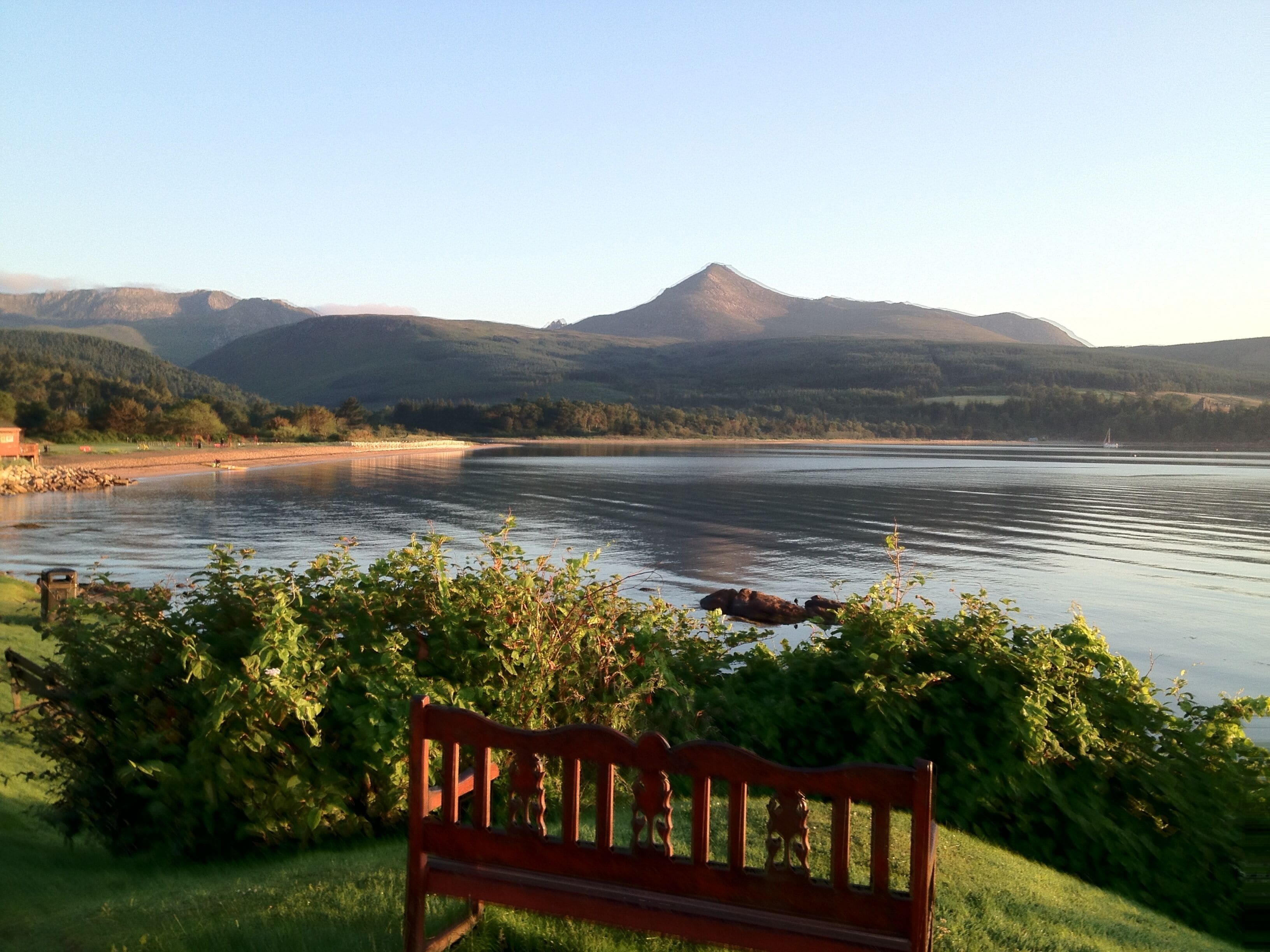 A bench overlooking a lake with mountains in the background.