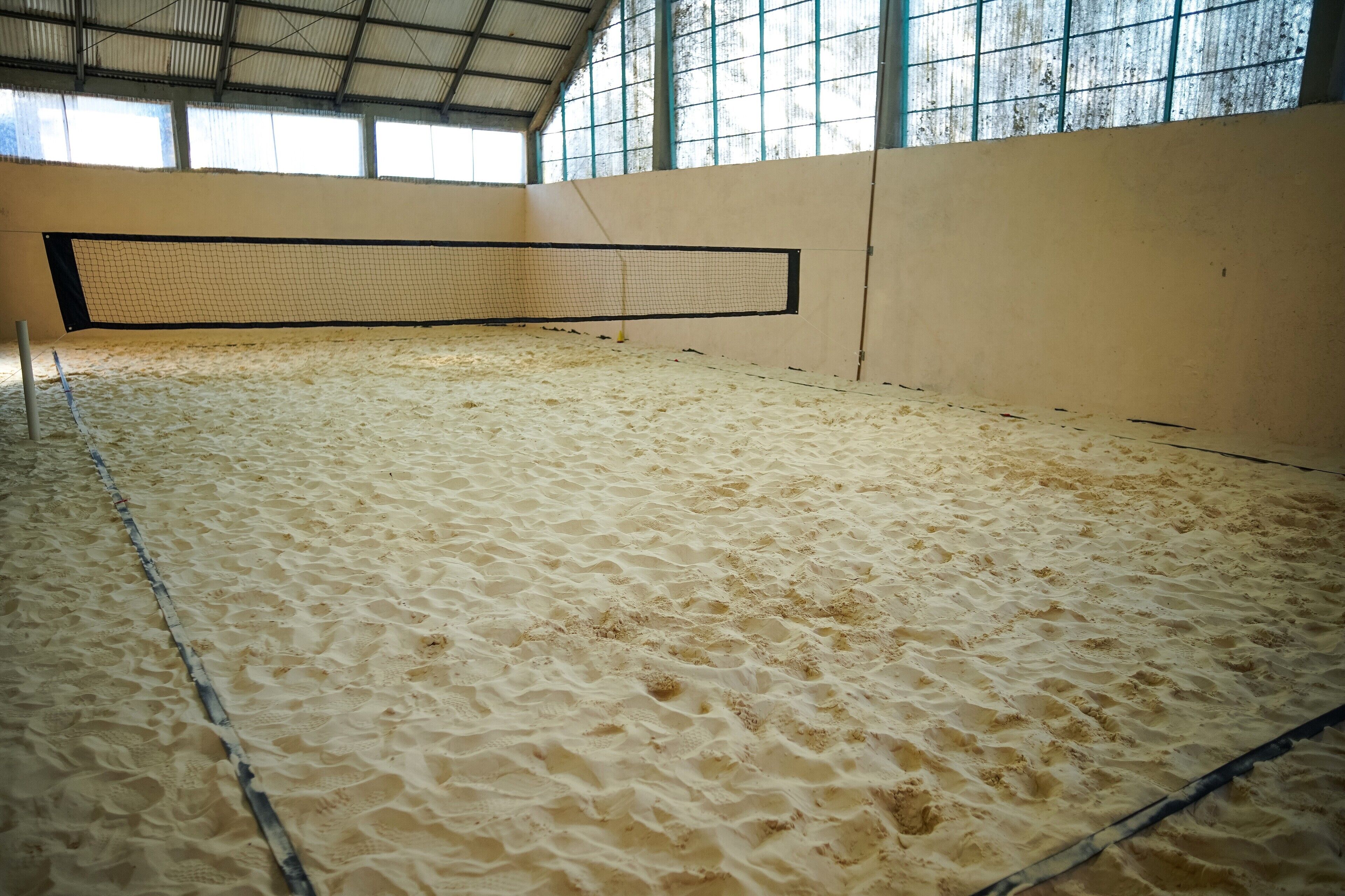 Una cancha de tenis interior con piso de arena y una red.