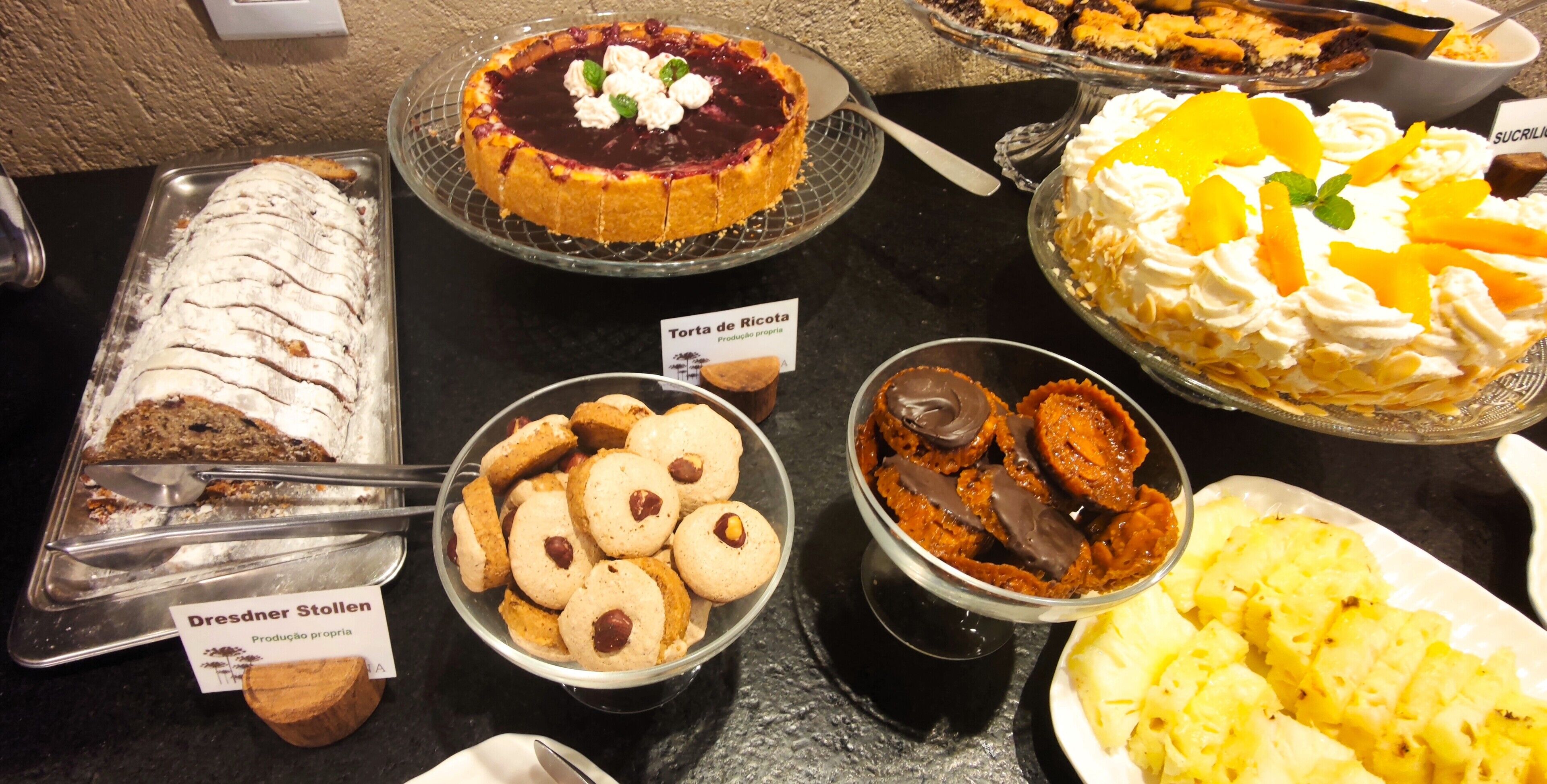 Diverse desserts te zien, waaronder een taart met slagroom en fruit, een bakje en koekjes.