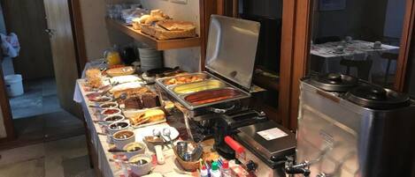 Una mesa de buffet con diferentes alimentos y una máquina de café.