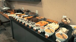 Un buffet proposant une variété de plats, notamment des gâteaux, des pâtisseries et des céréales.