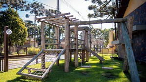 Une structure de jeux en bois, dotée d’un mur d’escalade et de balançoires, installée dans un espace verdoyant.