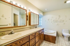 A bathroom with two sinks, a vanity with wooden drawers, a bathtub, and a toilet. - Kinglet 28 (Bend)