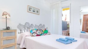 A bedroom with a bed, a bedside table, a lamp, and a window with curtains. - Fleming by Interhome (Lloret de Mar)