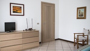Una habitació amb un aparador de fusta, una televisió, una porta i dos quadres a la paret.
