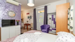 Ein Hotelzimmer mit Bett, Fernseher, Schreibtisch, Stuhl und Klimaanlage.