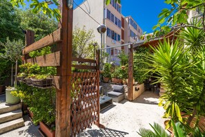 A patio area with outdoor seating, potted plants, and a wooden gate. - Apartments and Room Frane - Studio with Terrace (Dubrovnik)