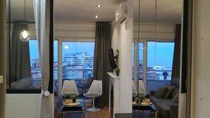 Una sala de estar moderna con vista a la ciudad, un sofá, dos sillones, una mesa de centro y un televisor.