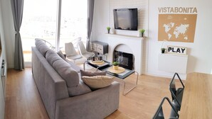 Una sala de estar moderna con un sofá gris, un televisor de pantalla plana, una chimenea y un mapa mundial en la pared.