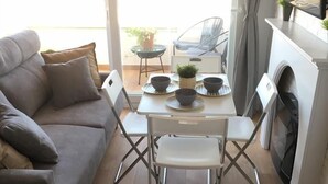 Una sala de estar moderna con un sofá gris, una mesa de comedor con sillas y una chimenea.