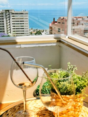A balcony with a view of the sea, a glass of wine, and a small plant. - Luxury apartment (Torremolinos)