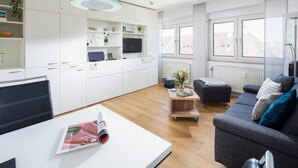 Un appartement moderne comprenant une cuisine, un coin repas et un salon. Il est équipé d’un canapé, d’une table basse et d’un téléviseur.