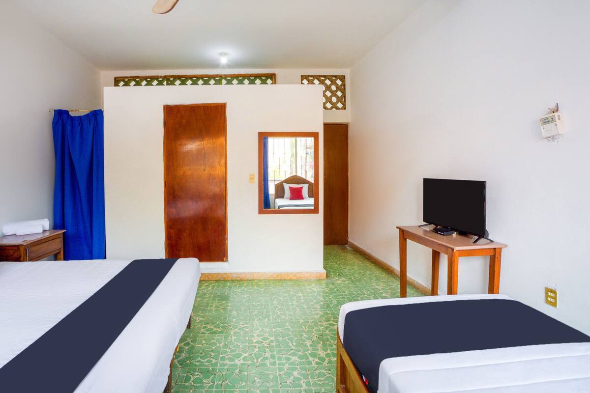 Habitació d'hotel amb dos llits, televisió i bany amb cortina de dutxa.