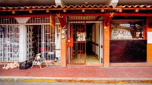 Fachada con acceso de baldosas, una reja metálica y un cartel.