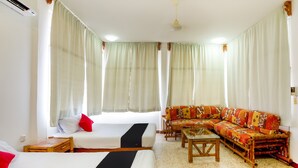 Una habitación de hotel con una cama, un sofá, una mesita y una ventana con cortinas.