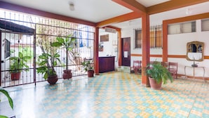 Amplia zona de recepción con suelo de baldosas, plantas en macetas y un mostrador de recepción.