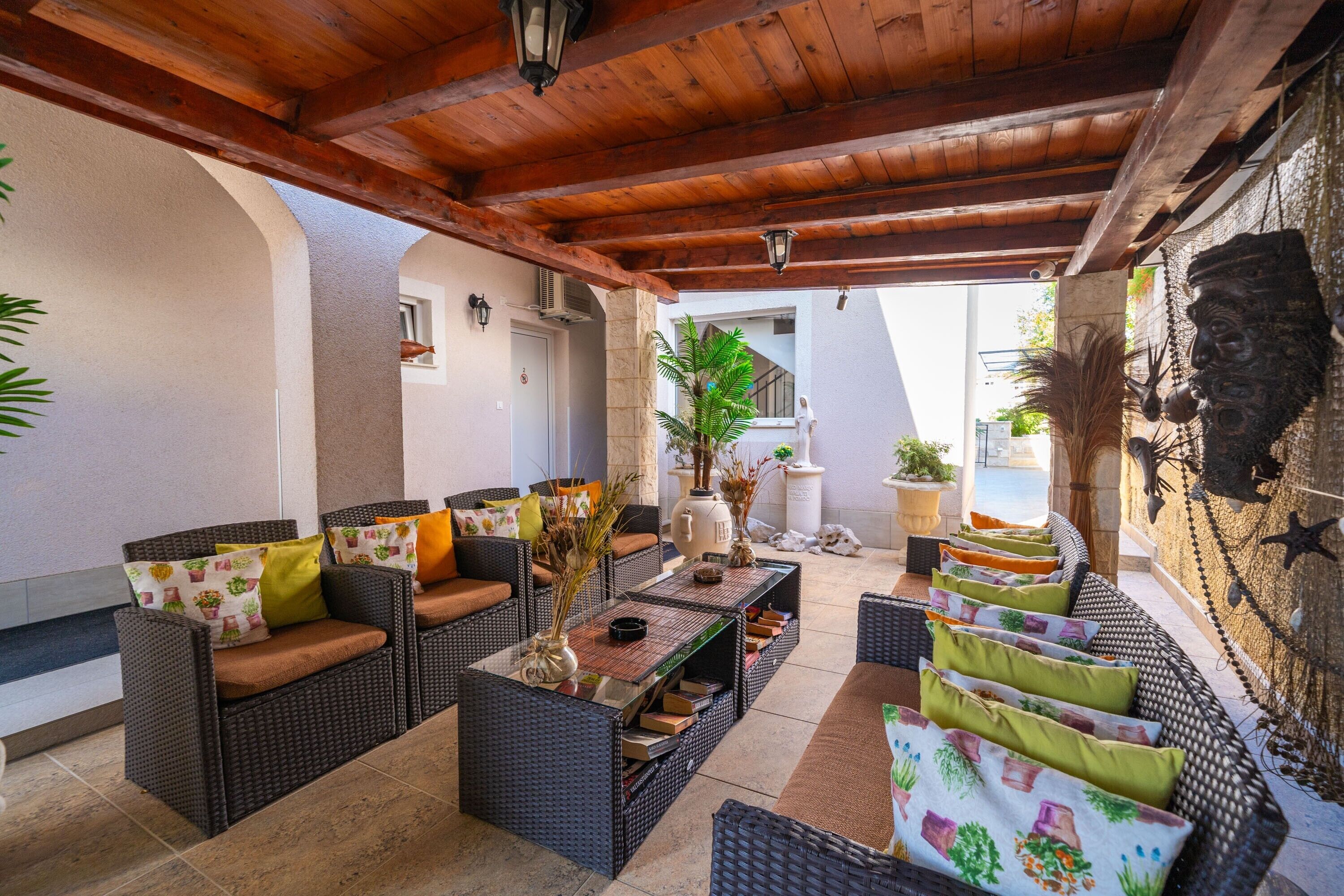 Un área de estar al aire libre con muebles de mimbre, una mesa baja y plantas decorativas.