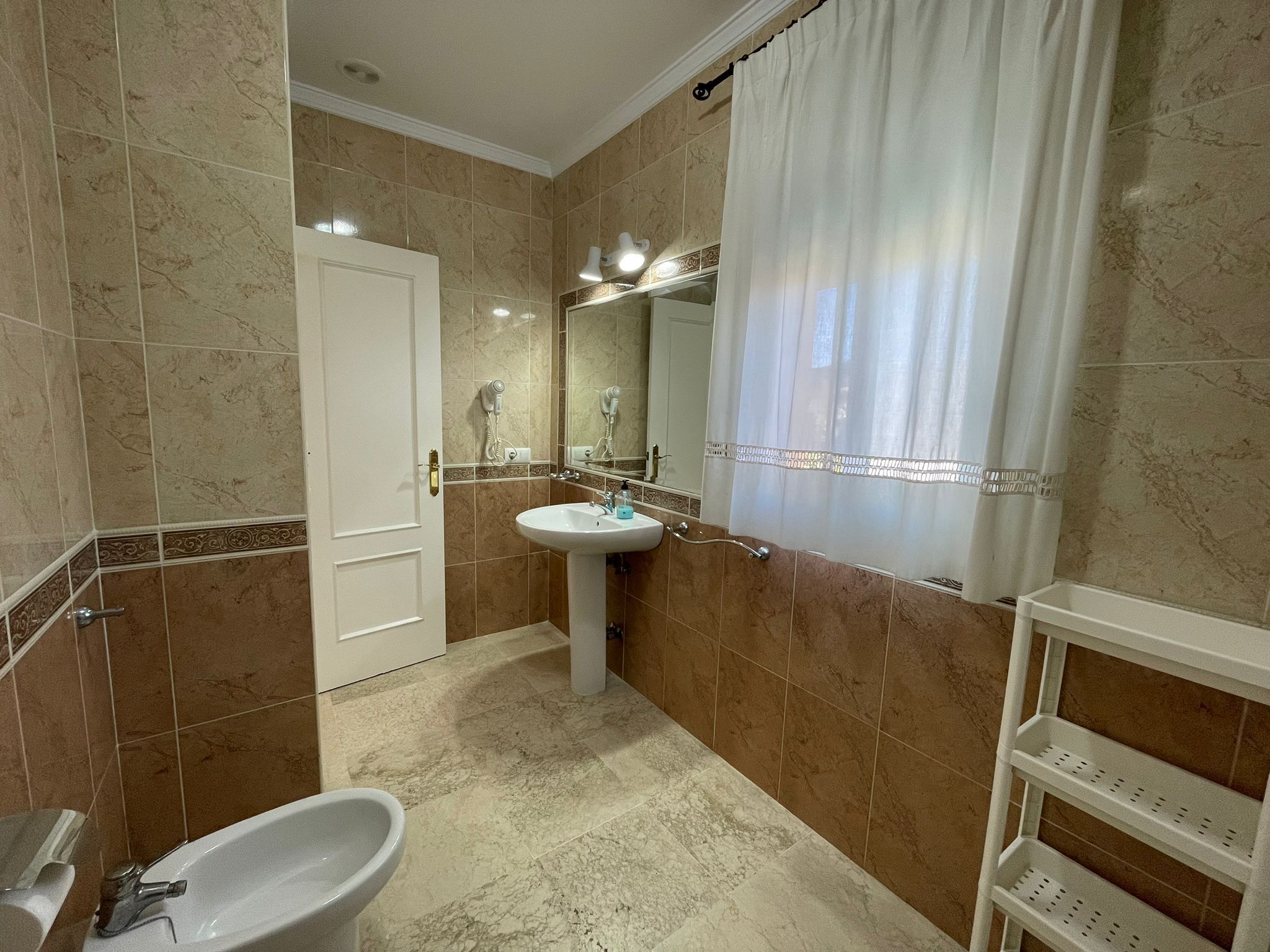 A bathroom with a white sink, a mirror, a white bathtub, and a shower curtain.