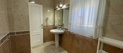 A bathroom with a white sink, a mirror, a white bathtub, and a shower curtain.