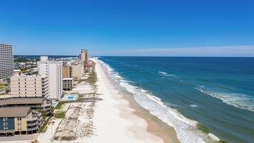 Un hotel frente al mar con varias construcciones, una playa y vistas al océano.