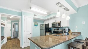 A kitchen with a granite countertop, stainless steel appliances, and pendant lighting. - Seacrest ~ Beach Front Condo (Gulf Shores)