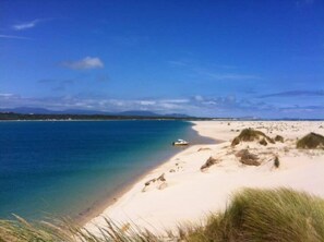 A beach with clear blue water, a sandy shore, and a boat. - Prom Coast 4~ Slice of Paradise ~ Stunning Beach! (Sandy Point)