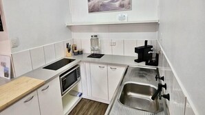 A compact kitchen with white cabinetry, a stainless steel sink, a microwave, and a coffee maker. - Prom Coast 4~ Slice of Paradise ~ Stunning Beach! (Sandy Point)