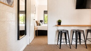 A hotel room with a bed, a desk, a TV, and a small plant. - Prom Coast 4~ Slice of Paradise ~ Stunning Beach! (Sandy Point)