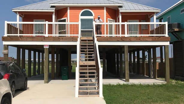 Een huis met twee verdiepingen, voorzien van een balkon en een trap naar de bovenverdieping.