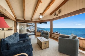 A cozy interior with a view of the sea, featuring a wooden ceiling, a red lamp, and a seating area with a view.