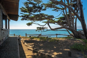 A wooden building with a view of the ocean and a large tree in the foreground. - Welcome to Titus Point! Breathtaking Oceanfront Escape with Panoramic Views! (Cambria)