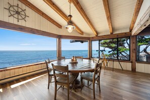 A wooden dining area with a view of the ocean, a telescope, and a ship's wheel on the wall. - Welcome to Titus Point! Breathtaking Oceanfront Escape with Panoramic Views! (Cambria)