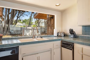 A kitchen with a large window, a sink, a dishwasher, and a toaster.
