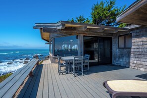 Una terraza de madera con cerramiento de vidrio que da al océano.