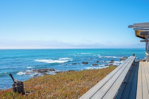 A wooden deck overlooking a rocky coastline with the ocean in the background.