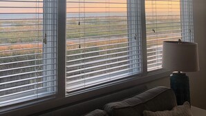 Ein Zimmer mit großen Fenstern, einem Sofa und einer Lampe.