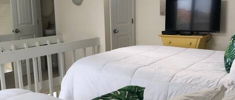 Un dormitorio con cama, televisor y ventana.
