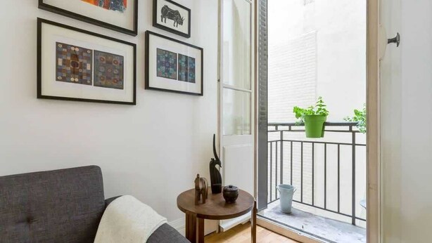 A room with a grey sofa, a small round table with a vase, and a balcony with potted plants. - République - Furnished apartment - Downtown Lyon (Lyon)