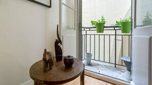 A small round table with a wooden sculpture and a black pot, a door, and a balcony with green potted plants. - République - Furnished apartment - Downtown Lyon (Lyon)