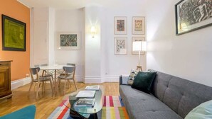 A living room with a sofa, a coffee table, a dining table with chairs, and framed artwork on the walls. - République - Furnished apartment - Downtown Lyon (Lyon)