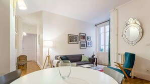 A living room with a round table, a sofa, a chair, and a mirror on the wall. - République - Furnished apartment - Downtown Lyon (Lyon)