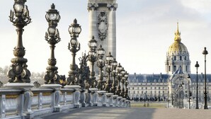 Una avenida amplia bordeada de faroles decorativos y un edificio clásico grande con una cúpula dorada al fondo.