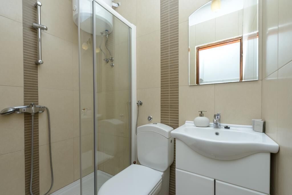 Ein modernes Badezimmer mit Duschkabine aus Glas, einer weißen Toilette und einem Waschbecken mit Spiegel.