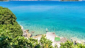 A coastal landscape with clear blue waters, a rocky shoreline, and a distant mountain range. - Apartments Nikolina (LU) - Studio with Sea View (3 Adults) (Lumbarda)