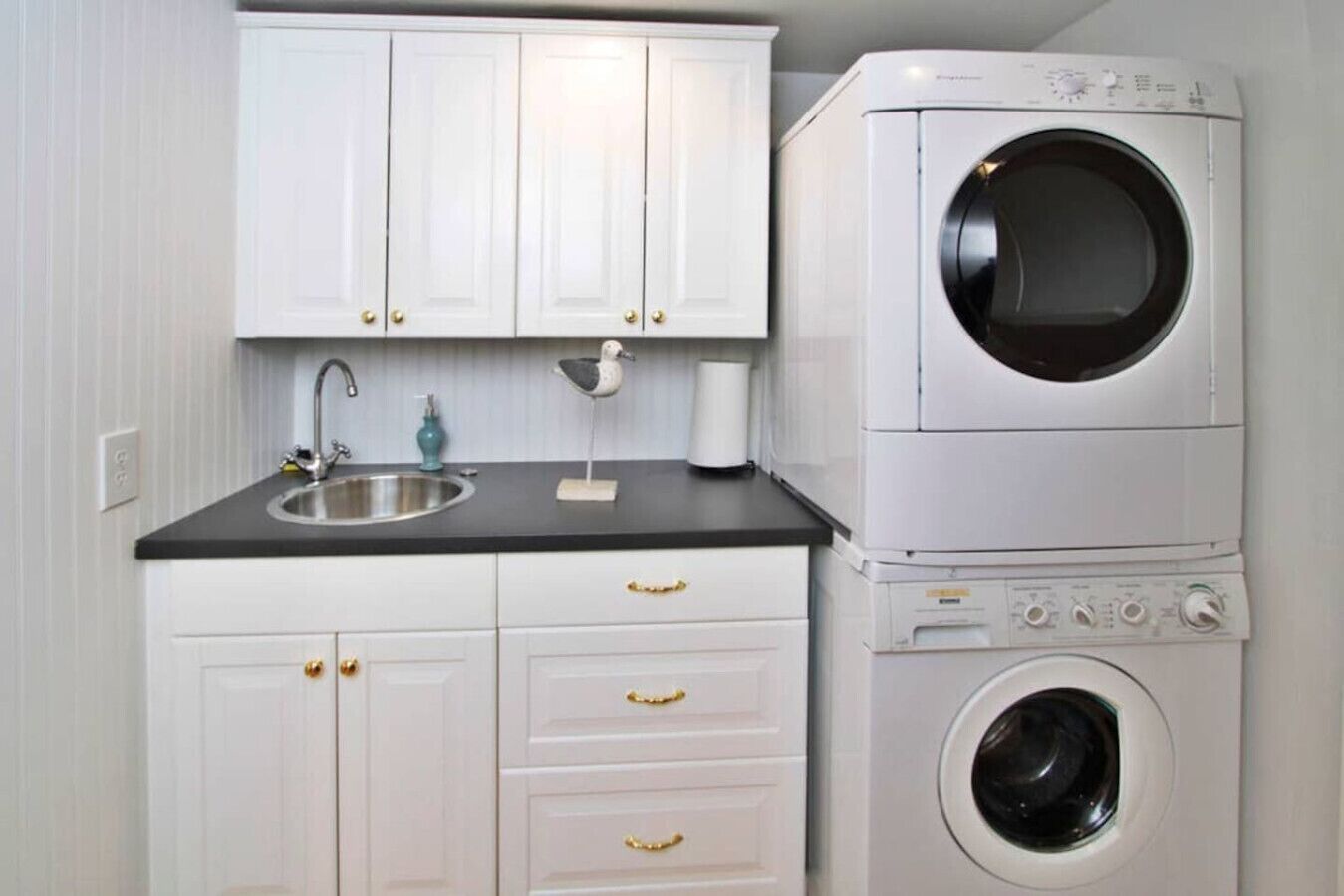 A compact laundry room with a washing machine, a sink, and cabinets.