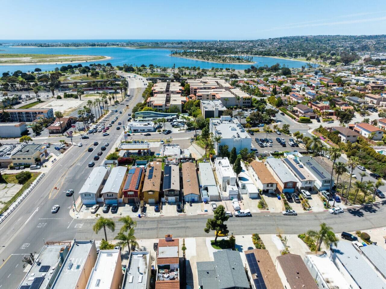 Vista aérea de un pueblo costero con un puerto deportivo, edificios residenciales y una calle principal.